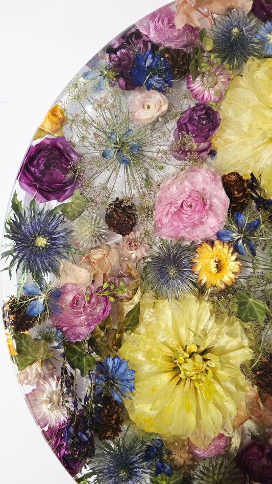 450mm Round Flower Board, complete with Lazy Susan, featuring  real preserved Nigella, Paper Daisies, Delphinium, Ivy,  Ranunculus, Dahlias, Chocolate Queen Annes Lace, Roses, Sea Holly, Hardenbergia & mini Pinecones set in Resin