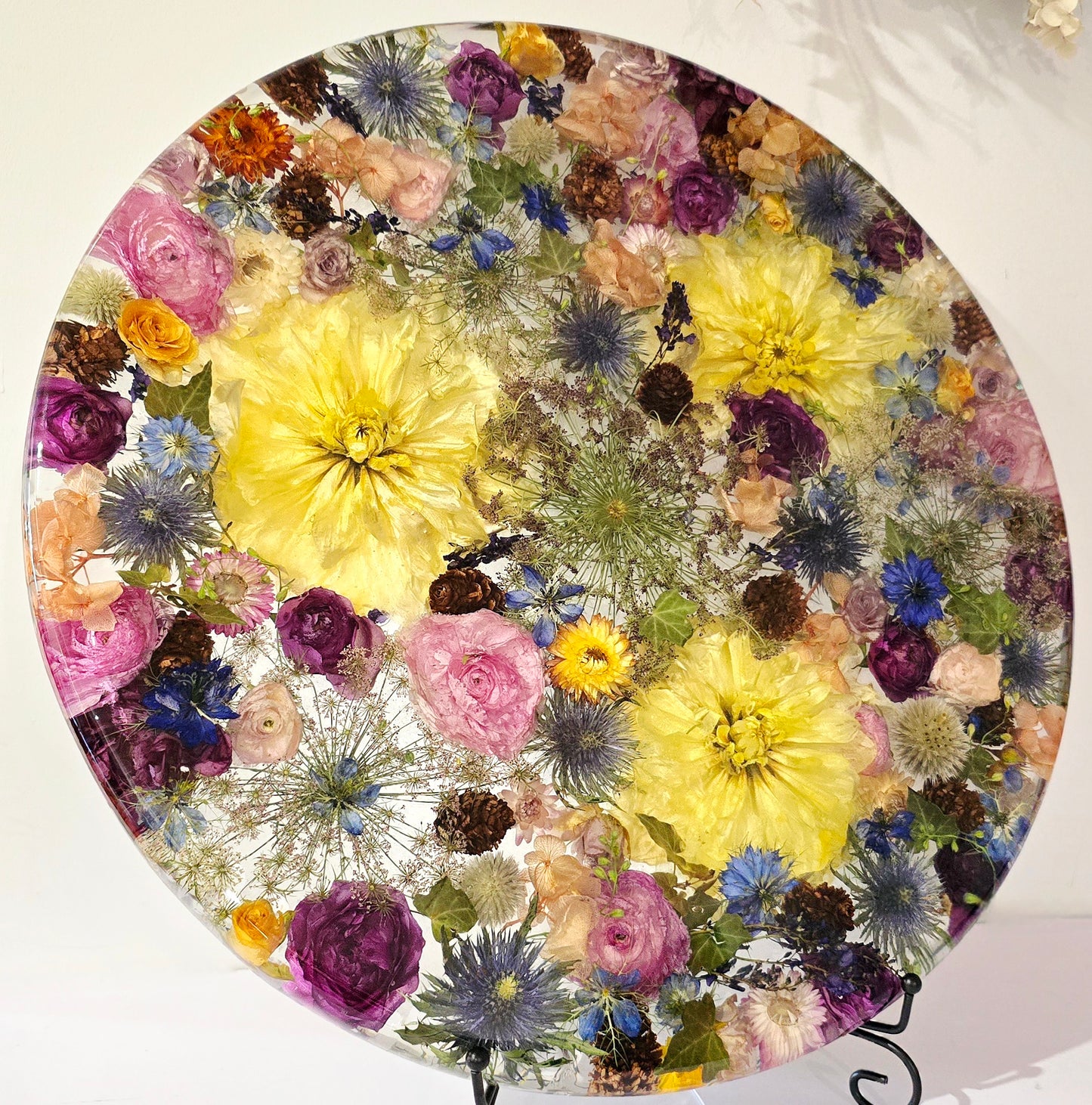 450mm Round Flower Board, complete with Lazy Susan, featuring  real preserved Nigella, Paper Daisies, Delphinium, Ivy,  Ranunculus, Dahlias, Chocolate Queen Annes Lace, Roses, Sea Holly, Hardenbergia & mini Pinecones set in Resin