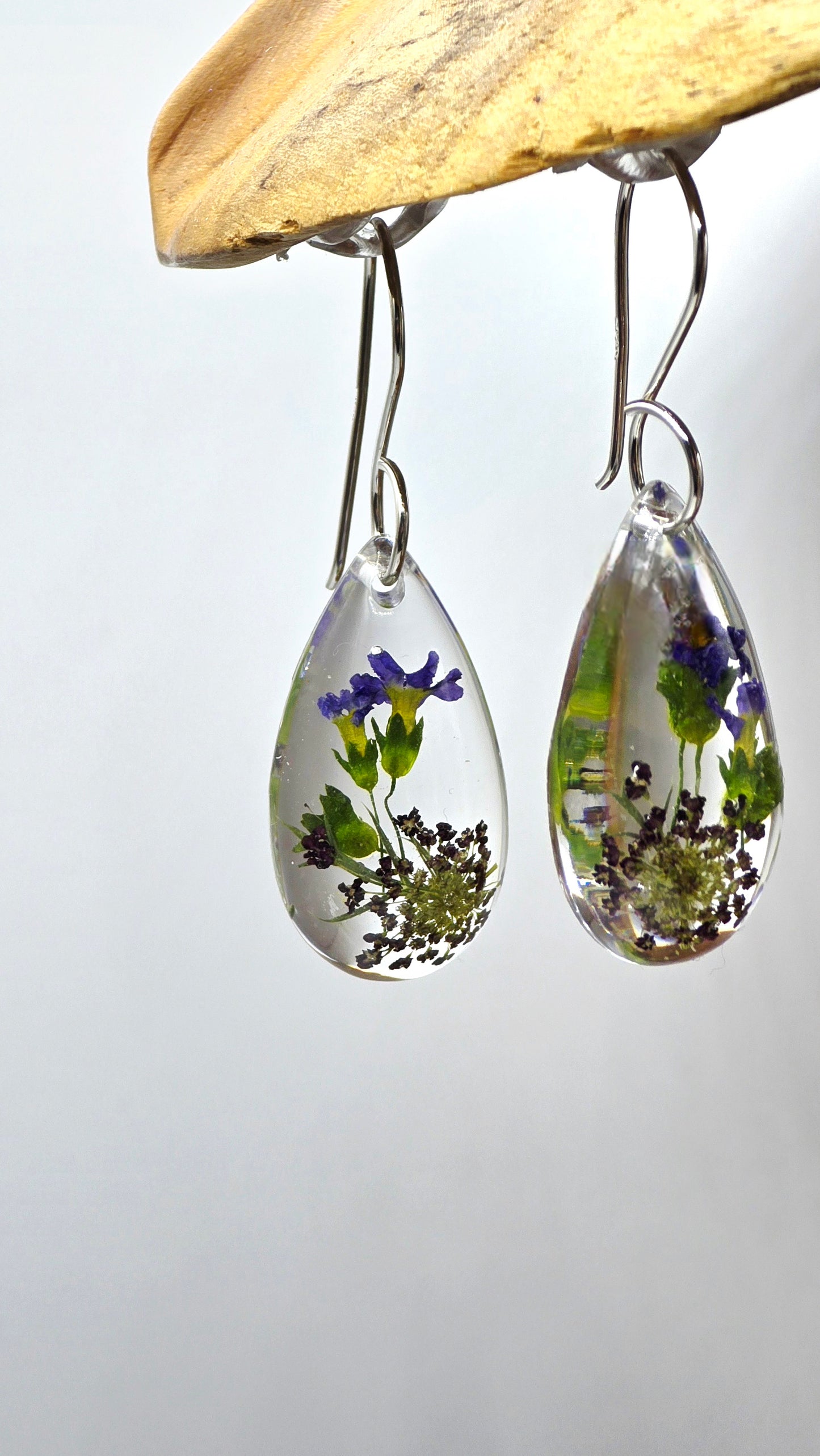 Earrings featuring wildflower specimens of Preserved Primula & Chocolate Queen Annes Lace, secured on a .925 Sterling Silver Shepherd Hook